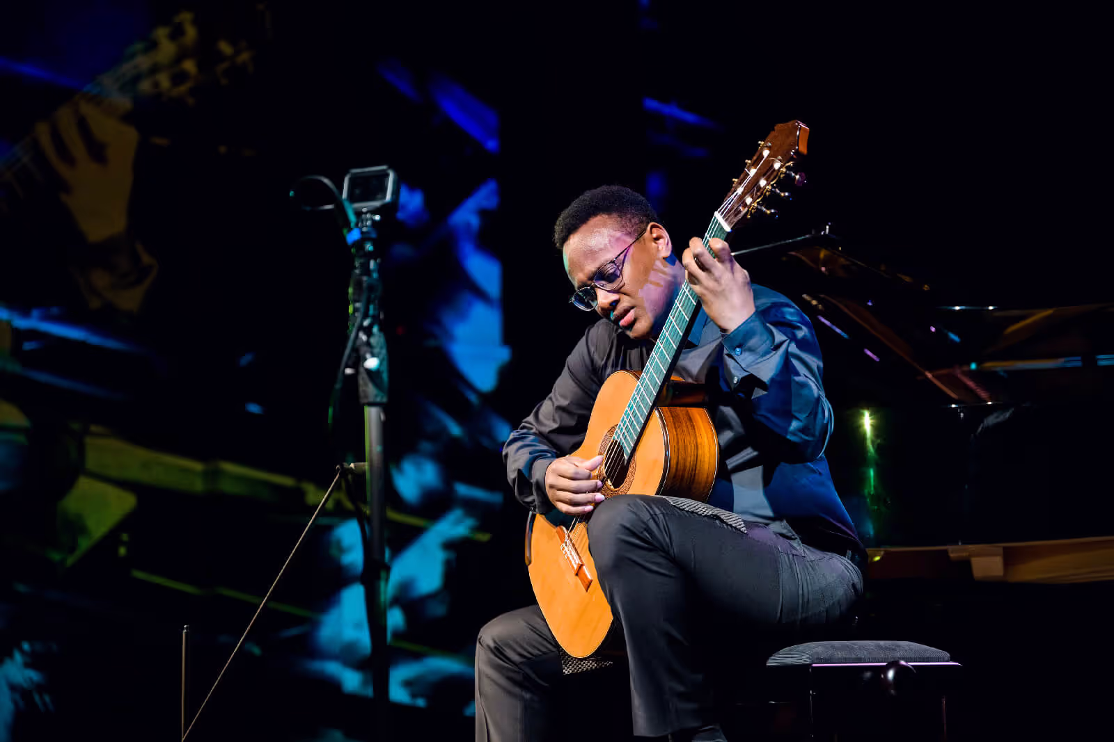 Portrait of Raphaël Feuillâtre with his guitar under blue lights